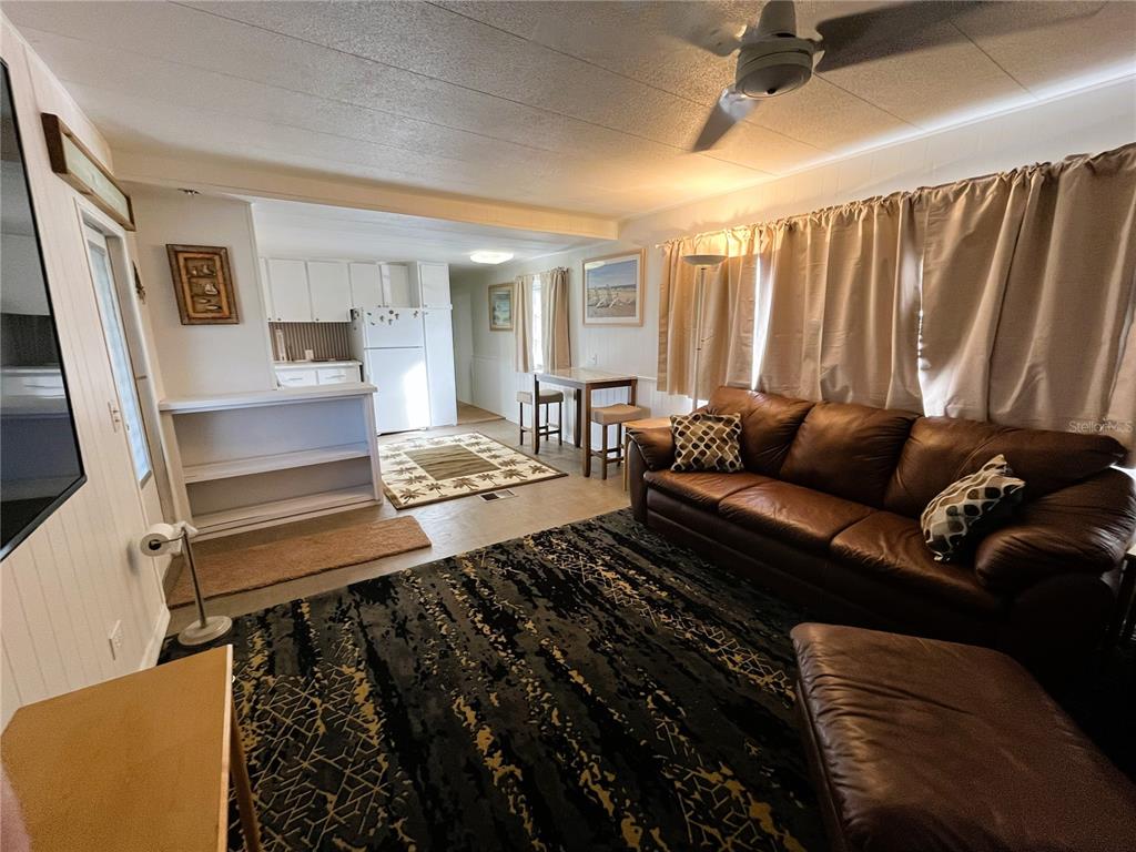 A living room with a brown leather sofa, patterned area rug, and an adjacent kitchen — 2113 ILLINOIS AVENUE, BRADENTON, FL