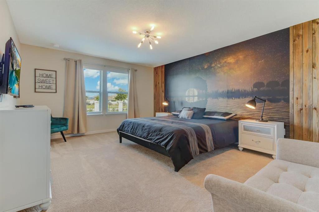 A bedroom features a large bed against a wall mural, a white dresser, and carpet — 2436 DUBAI STREET, KISSIMMEE, FL
