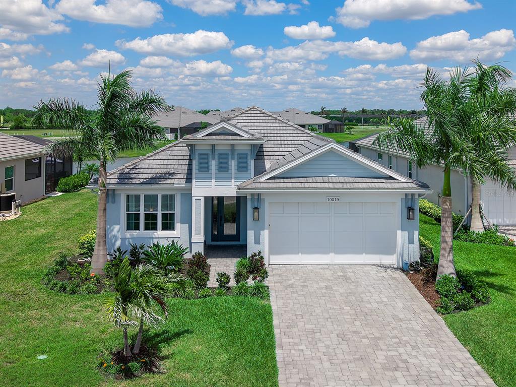A single-story house with a light blue exterior, a tiled roof, and a paved driveway — 10019 DEGAS TERRACE, BRADENTON, FL
