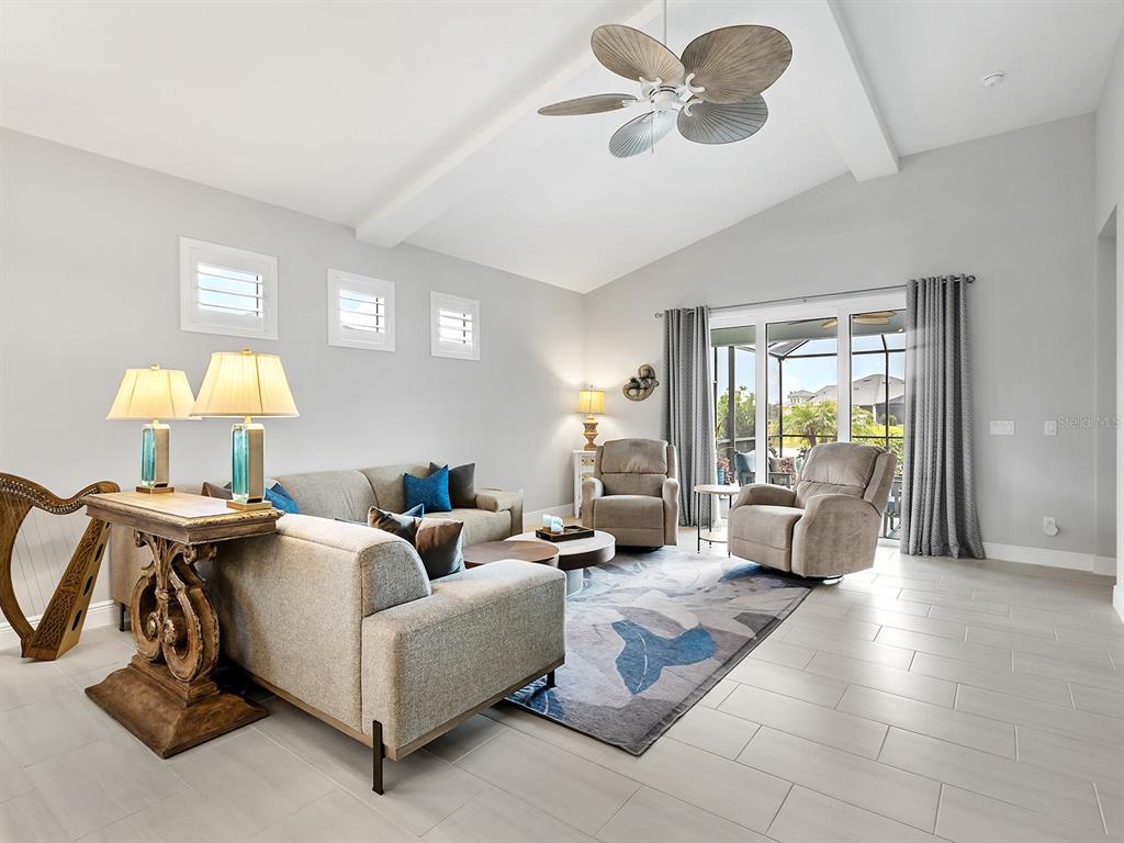 A living room features a vaulted ceiling, a ceiling fan, and a large area rug — 10019 DEGAS TERRACE, BRADENTON, FL