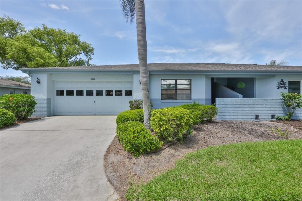 A single-story house features a two-car garage, a palm tree, and a brick facade — 1618 LELAND DRIVE, SUN CITY CENTER, FL