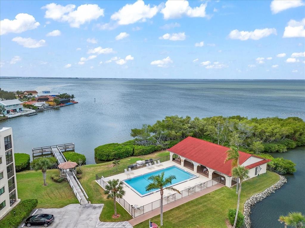 An aerial view shows a swimming pool and clubhouse next to a large body of water — 5800 N BANANA RIVER BOULEVARD UNIT 134, CAPE CANAVERAL, FL