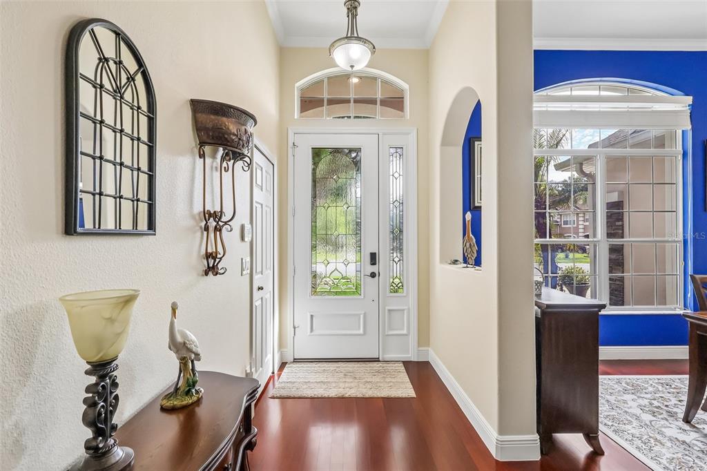 An entryway with hardwood floors, a white front door, and a blue-walled room beyond — 115 W BLUE WATER EDGE DRIVE, EUSTIS, FL