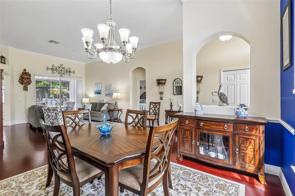 A dining room with a wooden table, chandelier, and a sideboard beneath an arched wall cutout — 115 W BLUE WATER EDGE DRIVE, EUSTIS, FL