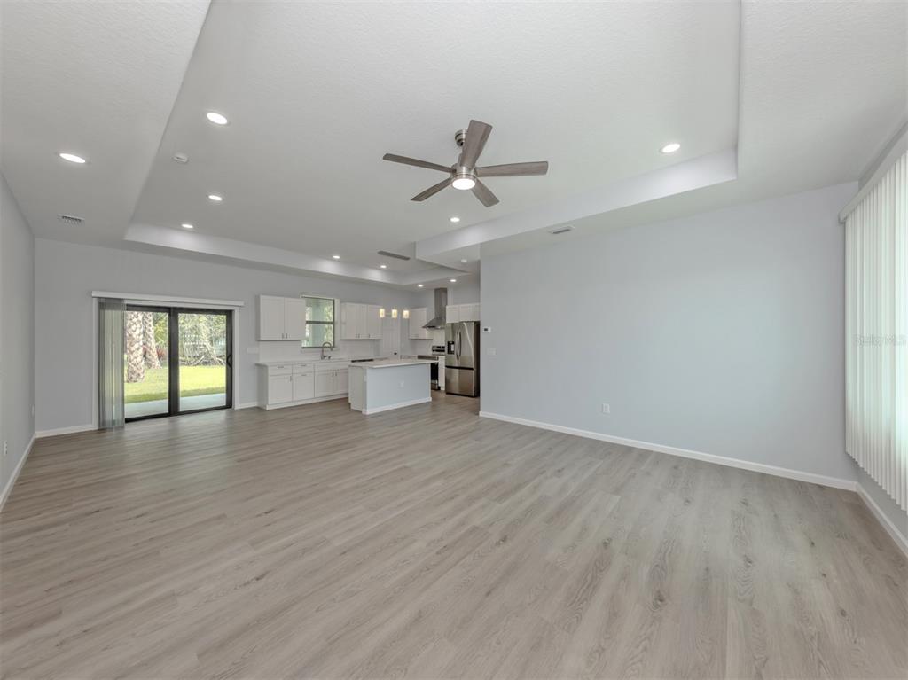 An open-concept living area features light wood-look flooring, a tray ceiling, and a modern kitchen — 3763 RAGEN STREET, NORTH PORT, FL