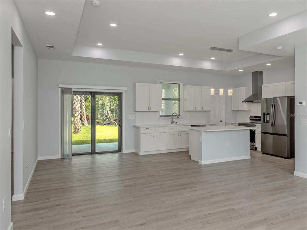 A modern kitchen with white cabinets, stainless steel appliances, and an island overlooks a backyard — 3763 RAGEN STREET, NORTH PORT, FL