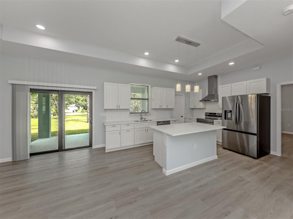 A modern kitchen features white cabinets, a central island, stainless steel appliances, and wood flooring — 3763 RAGEN STREET, NORTH PORT, FL