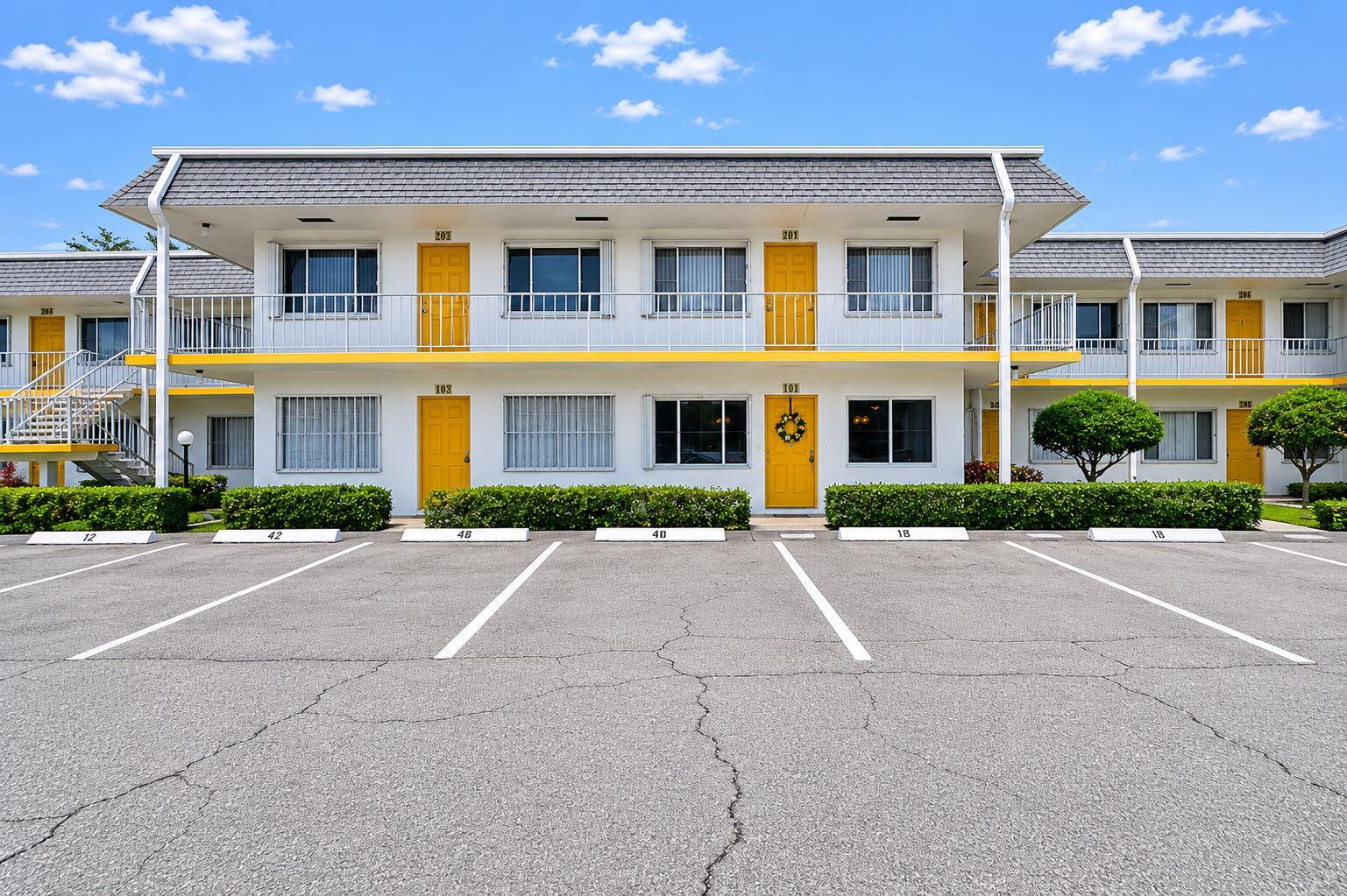 A two-story motel building features yellow doors, white exterior walls, and a parking lot — 3240 Lake Osborne Drive Apt 104, FL 33461, FL