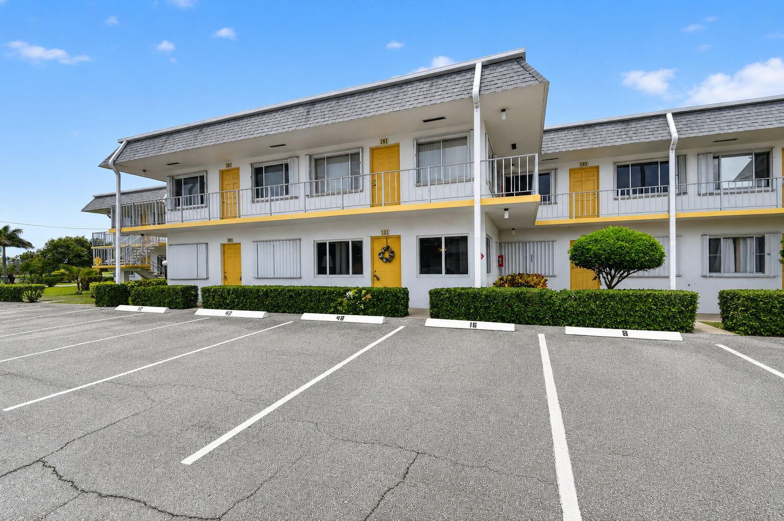 A two-story motel building with yellow doors, white exterior walls, and a parking lot — 3240 Lake Osborne Drive Apt 104, FL 33461, FL