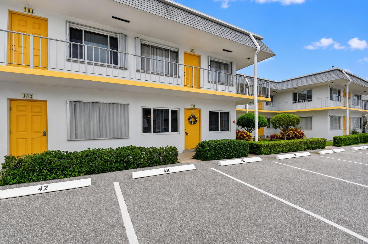 A two-story motel building features yellow doors, white exterior walls, and a paved parking lot — 3240 Lake Osborne Drive Apt 104, FL 33461, FL