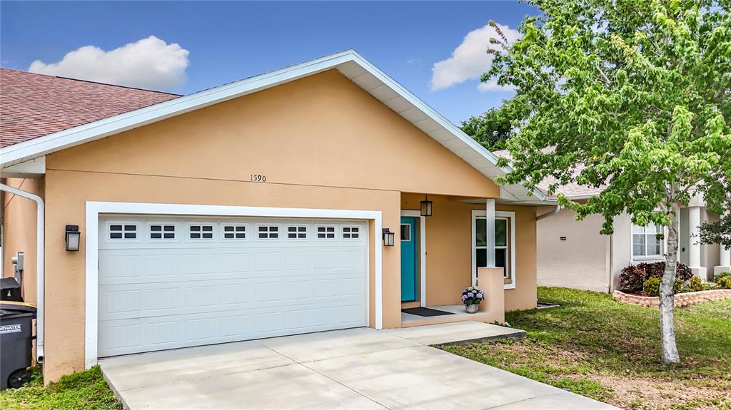 A single-story house with a tan stucco exterior, a two-car garage, and a teal door — 1590 BURNS DRIVE, CLEARWATER, FL