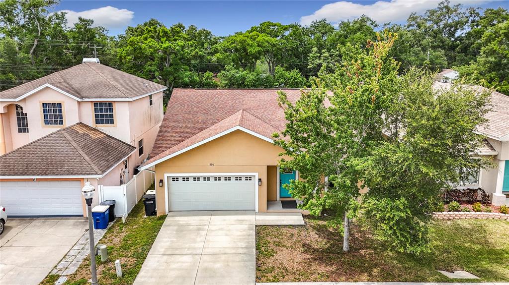 An aerial view shows a tan house with a two-car garage and a large tree — 1590 BURNS DRIVE, CLEARWATER, FL
