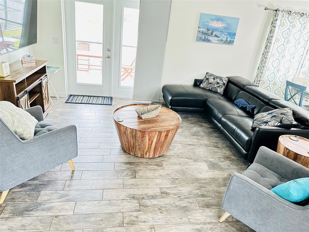 A living room features a black sectional sofa, two gray armchairs, and a round wooden table — 7076 NICHOLS STREET, ENGLEWOOD, FL