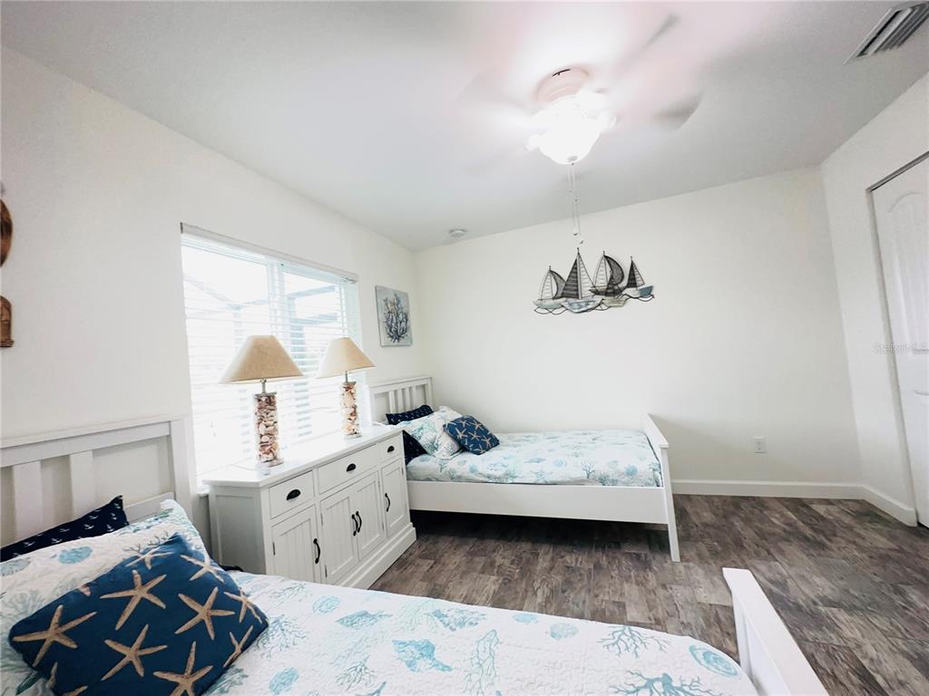 A bedroom features two twin beds, a white dresser with two lamps, and nautical wall decor — 7076 NICHOLS STREET, ENGLEWOOD, FL