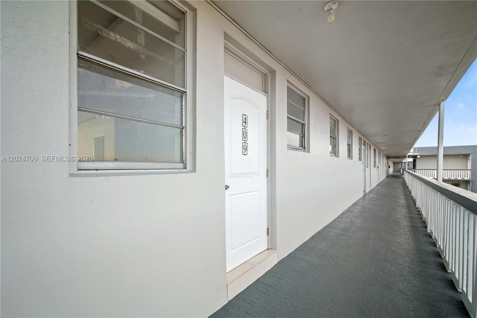 An exterior walkway features a white door labeled 409 and a white metal railing — 18601 NE 14th Ave # 409, Miami FL 33179, MIAMI, FL