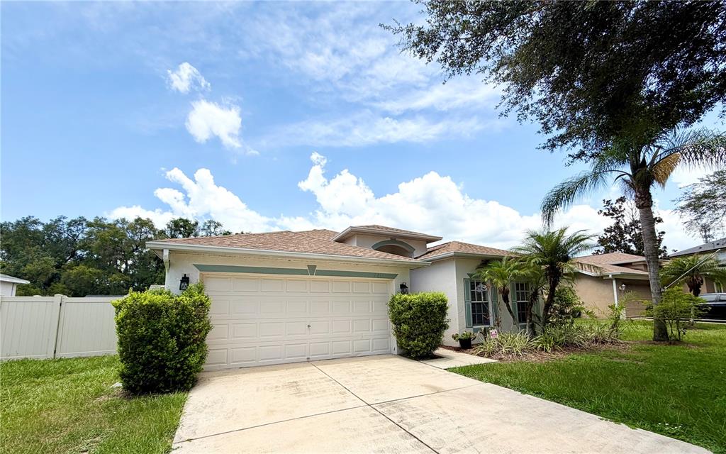 A single-story house with a two-car garage, light-colored stucco walls, and a shingled roof — 804 COADE STONE DRIVE, SEFFNER, FL