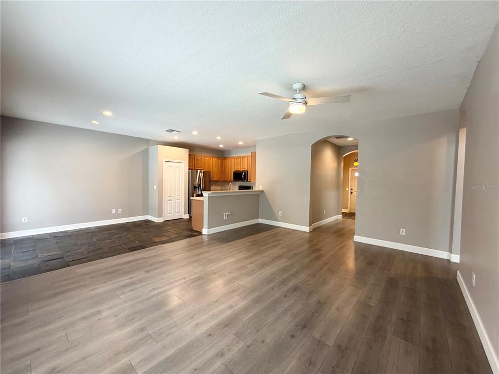 An open-concept living area features wood-look flooring, a kitchen with wood cabinets, and recessed lighting — 804 COADE STONE DRIVE, SEFFNER, FL