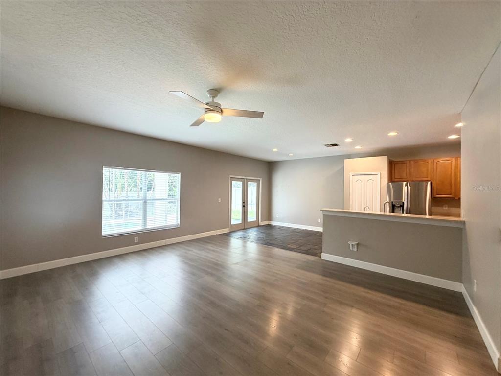 An open-concept living area features wood-look flooring, a ceiling fan, and an adjacent kitchen — 804 COADE STONE DRIVE, SEFFNER, FL