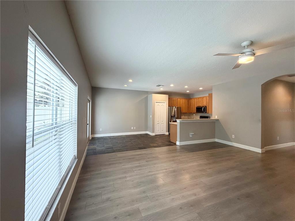 An open-concept living area features light wood-look flooring, a tiled kitchen space, and recessed lighting — 804 COADE STONE DRIVE, SEFFNER, FL