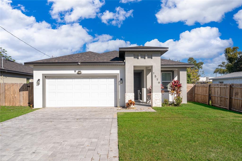 A single-story house with a white stucco facade, a two-car garage, and a paved driveway — 1519 INDIANA STREET, ORLANDO, FL