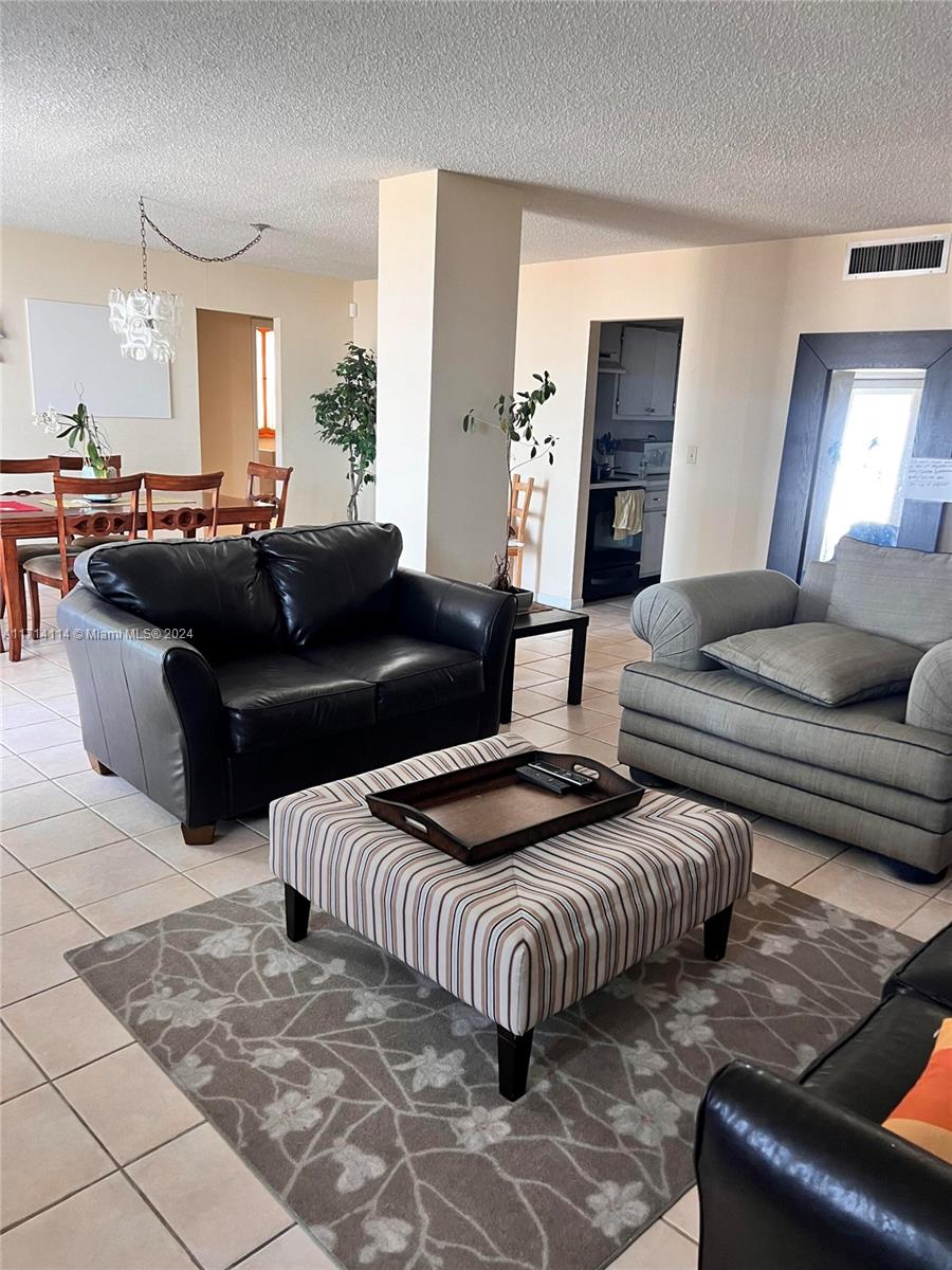 A living room features a black leather loveseat, a gray sofa, and a striped ottoman — 1410 S Ocean Dr # 804, Hollywood FL 33019, HOLLYWOOD, FL