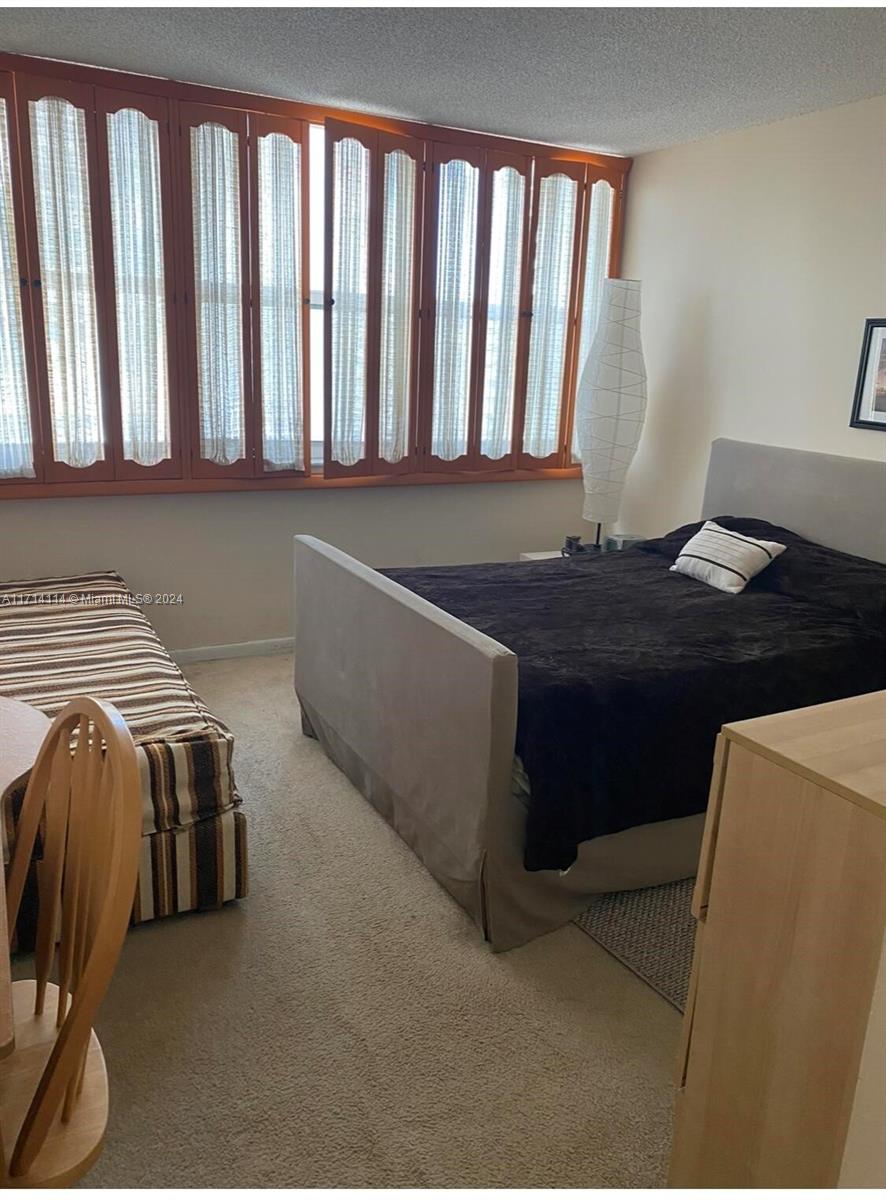 A bedroom features a bed, a striped daybed, and large wooden shutters covering the windows — 1410 S Ocean Dr # 804, Hollywood FL 33019, HOLLYWOOD, FL