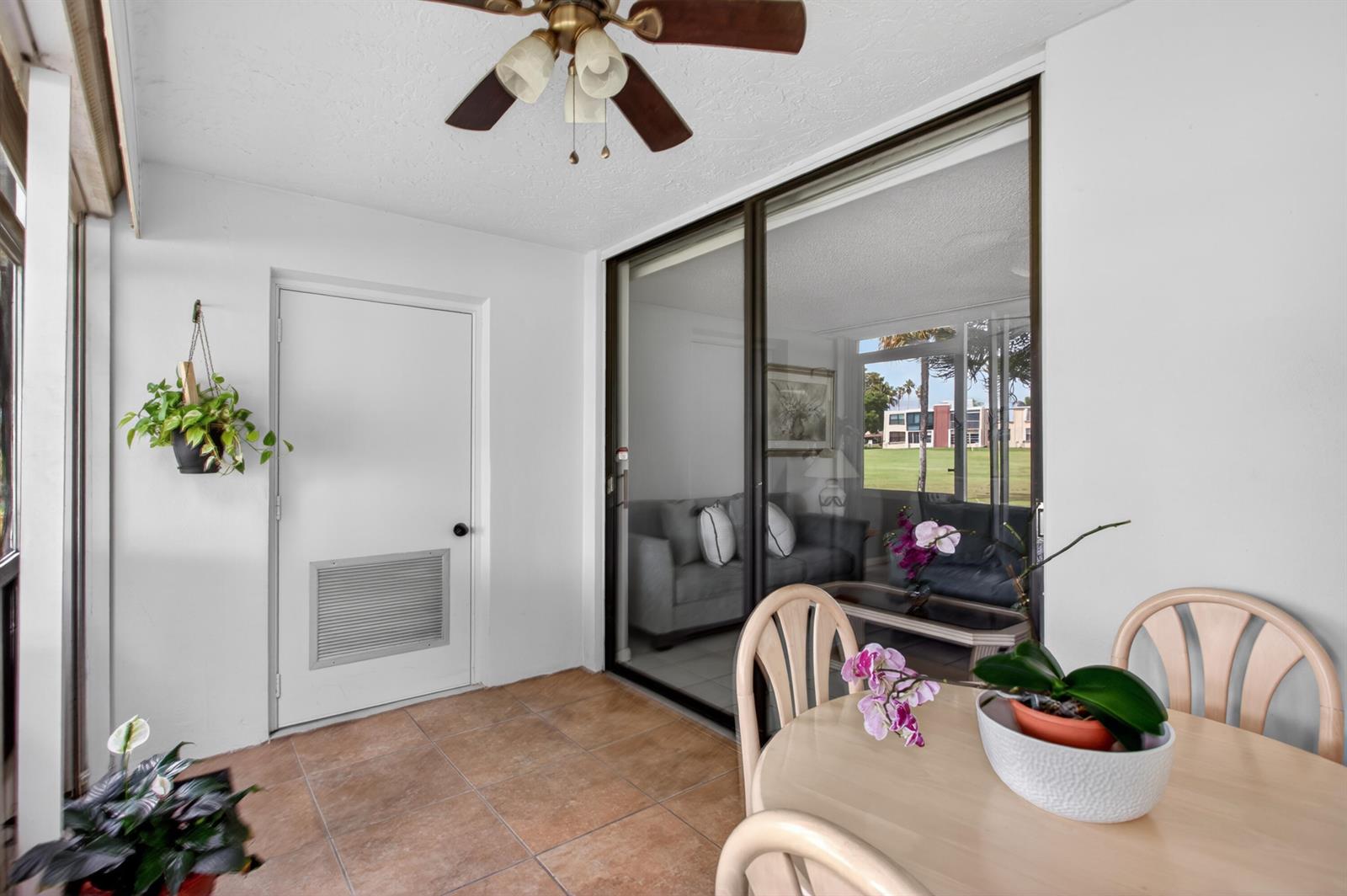 A tiled sunroom features a ceiling fan, a sliding glass door, and a dining set — 7321 NW 18th Street # 107, Margate FL 33063, MARGATE, FL
