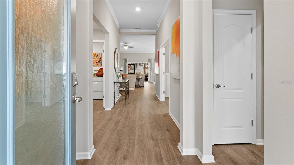 A bright entryway leads into a hallway with light wood flooring and a white door — 32 HARDWOOD TRAIL, PALM COAST, FL