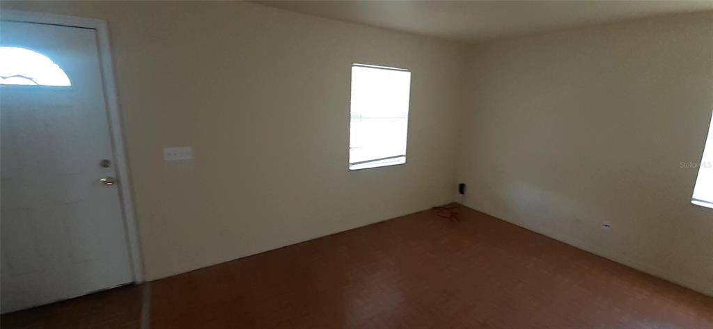 An empty room features beige walls, a white door with a window, and wood-look flooring — 4226 E PALIFOX STREET, TAMPA, FL
