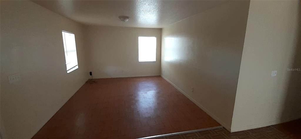 An empty room features light-colored walls, wood-look flooring, and two windows — 4226 E PALIFOX STREET, TAMPA, FL