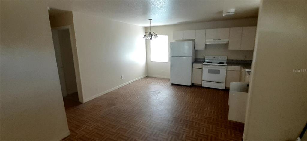 An open kitchen and dining area features white appliances, wooden cabinets, and parquet flooring — 4226 E PALIFOX STREET, TAMPA, FL