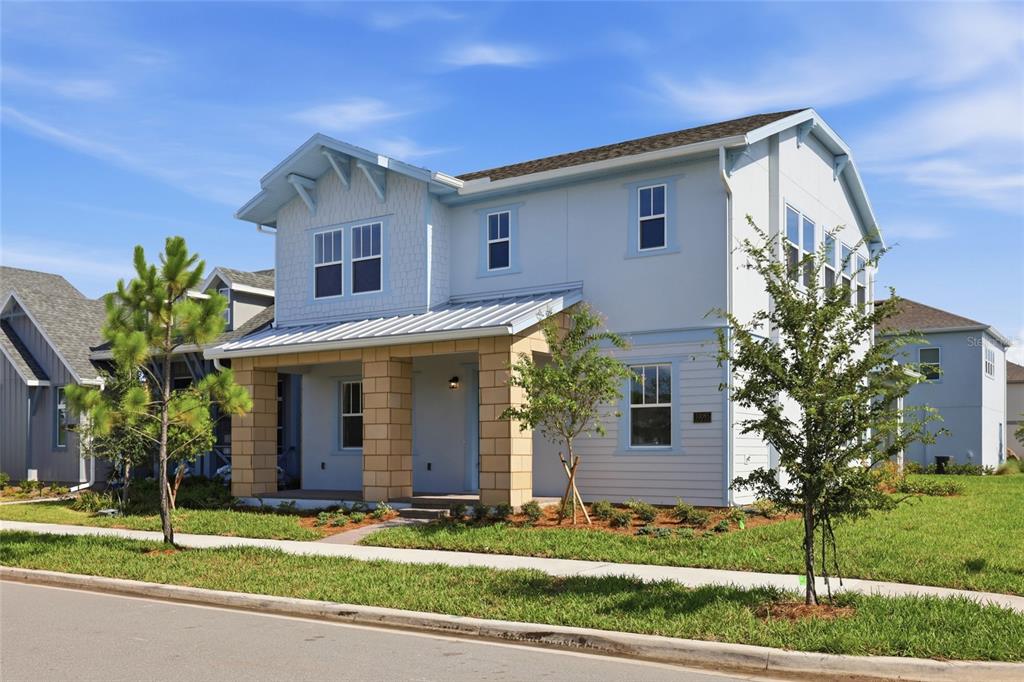 A two-story light blue house features a tan brick porch and a metal roof — 10085 BALLAST DRIVE, ORLANDO, FL