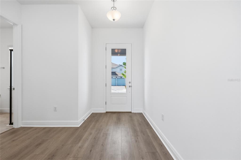 An entryway features light wood-look flooring, white walls, and a glass-paneled front door — 10085 BALLAST DRIVE, ORLANDO, FL