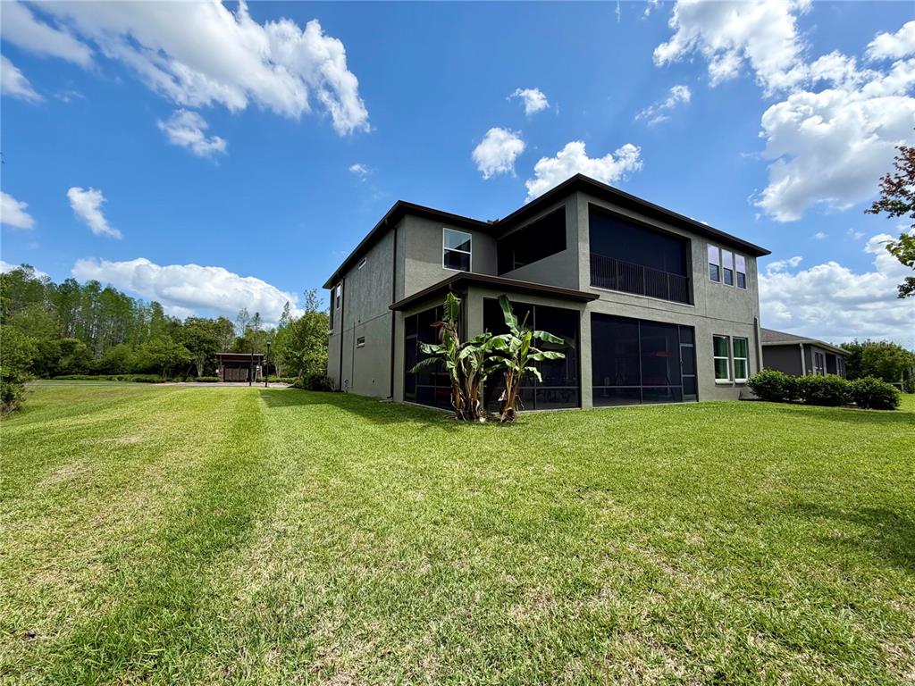 A two-story house features a screened-in patio and a second-story balcony with dark railings — 1879 WHITEWILLOW DRIVE, WESLEY CHAPEL, FL