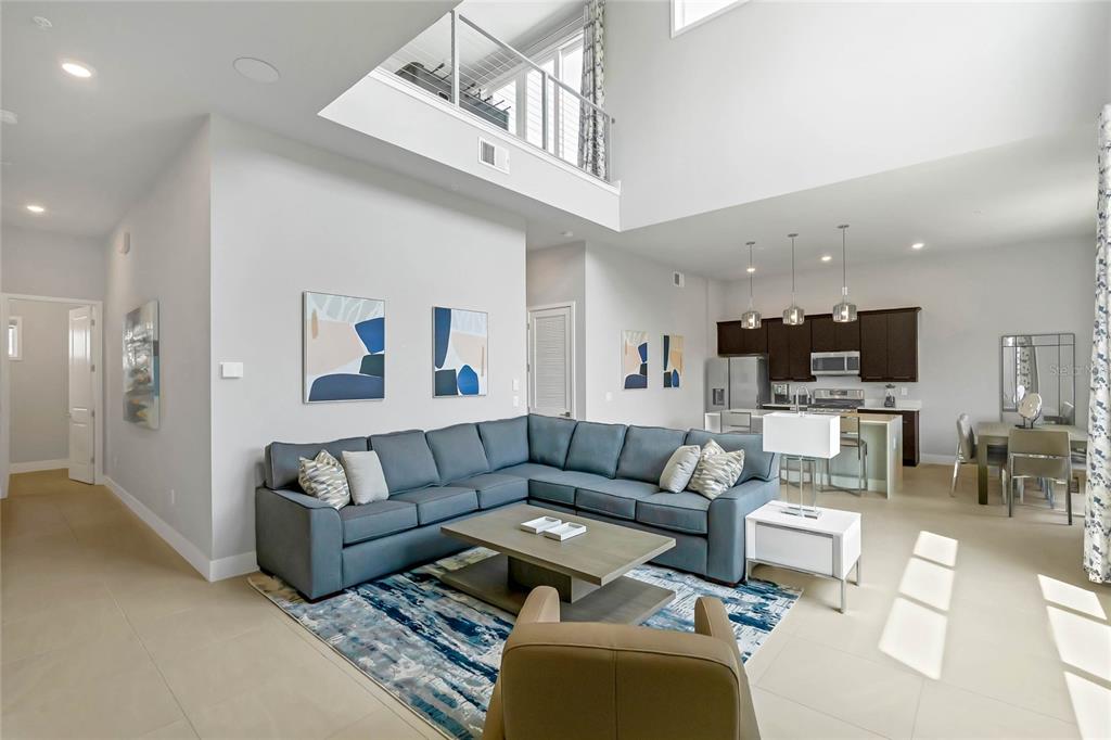 A spacious living room with a blue sectional sofa, area rug, and open kitchen — 7740 SANDY RIDGE DRIVE 241 BLDG 44, REUNION, FL