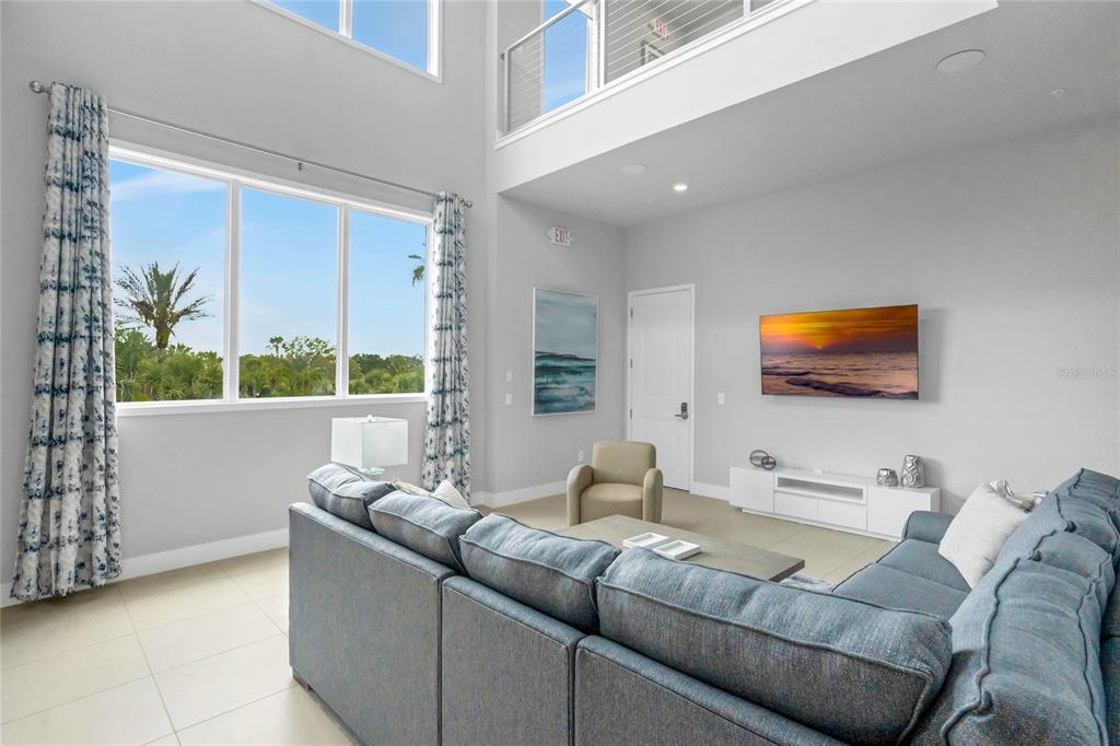 A living room with high ceilings, a large sectional sofa, and a wall-mounted television — 7740 SANDY RIDGE DRIVE 241 BLDG 44, REUNION, FL