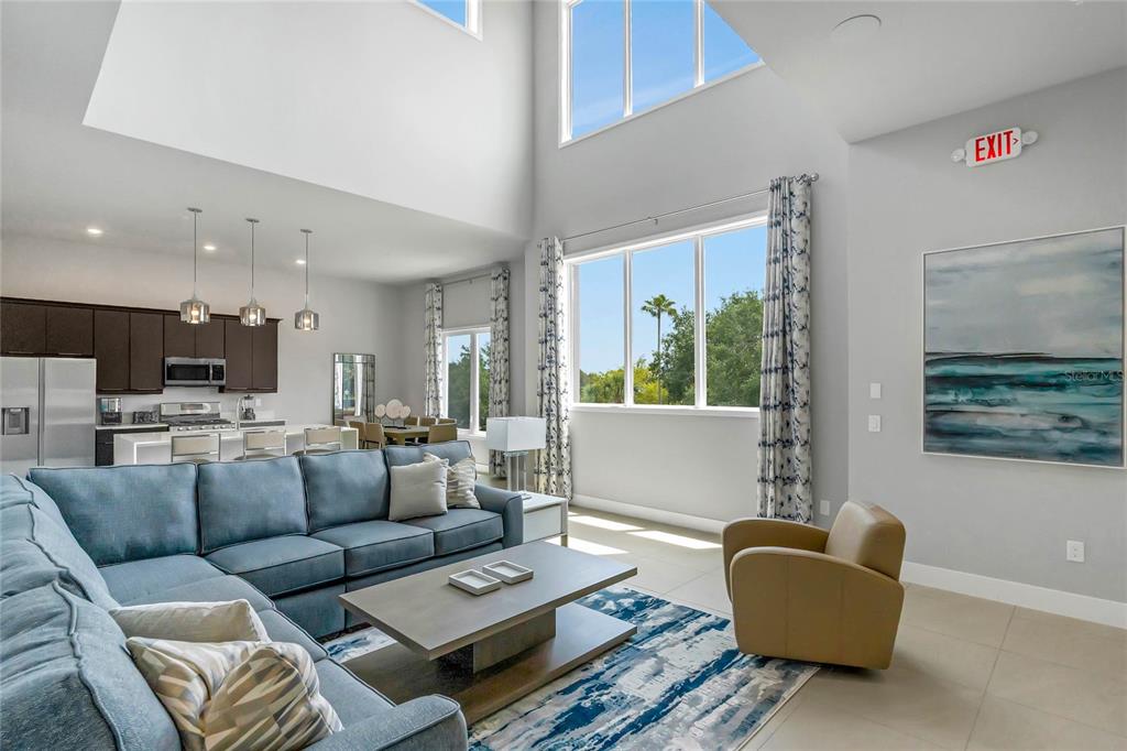 A living room with a blue sectional sofa, high ceilings, and an open kitchen — 7740 SANDY RIDGE DRIVE 241 BLDG 44, REUNION, FL