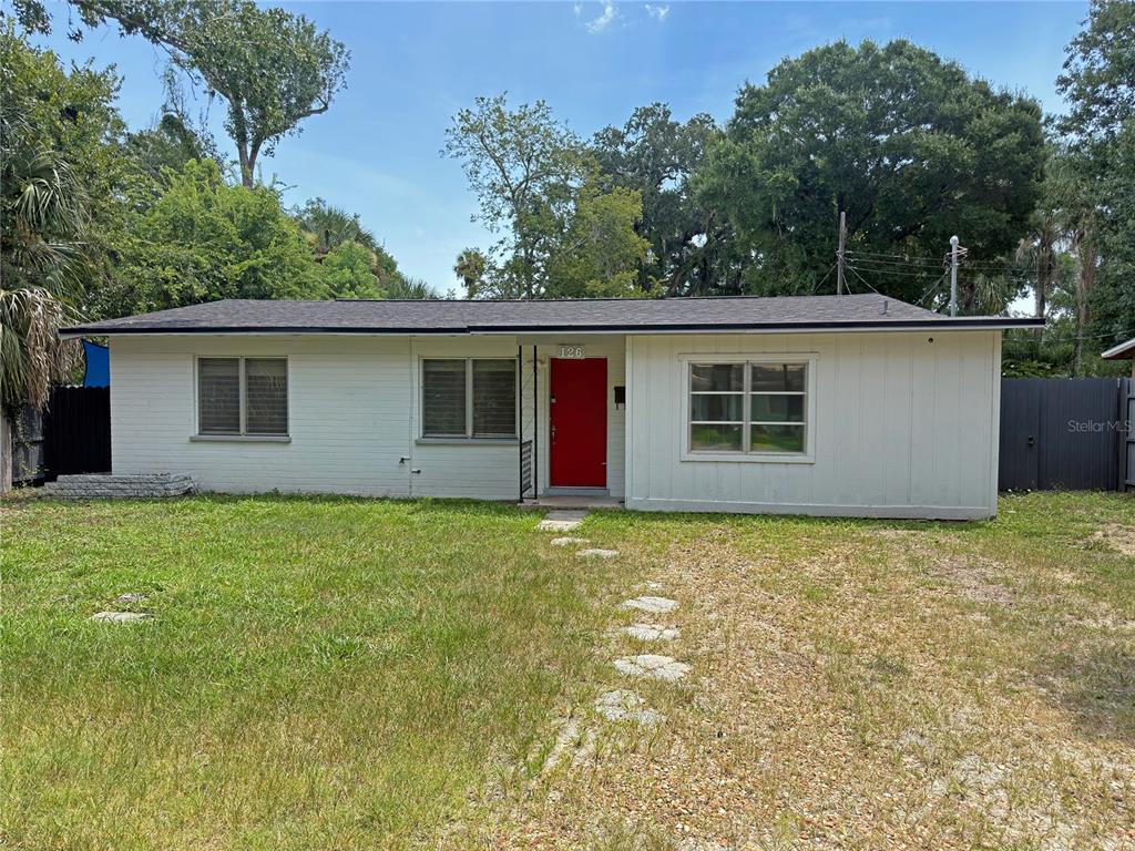 A single-story house with white siding, a red front door, and a gravel front yard — 126 PALM DRIVE, DAYTONA BEACH, FL