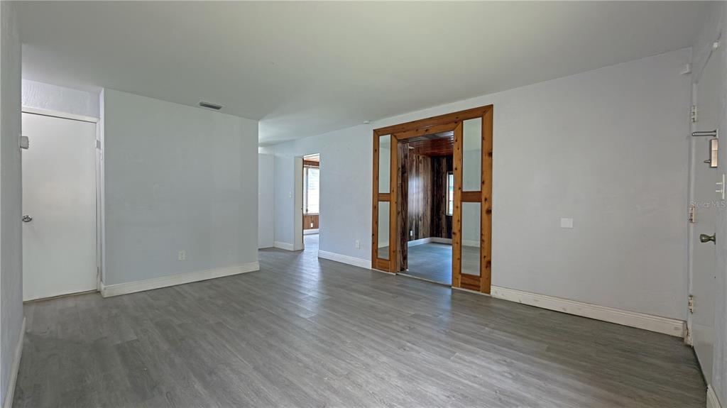 A room with gray walls, wood-look flooring, and a wooden-framed doorway leading to another room — 126 PALM DRIVE, DAYTONA BEACH, FL