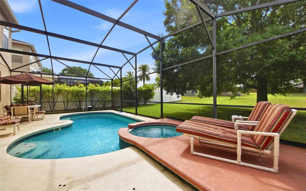 A screened-in patio features a swimming pool, a hot tub, and lounge chairs — 111 ALDRIDGE LANE, DAVENPORT, FL