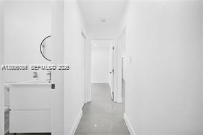 A white hallway leads to a doorway with a bathroom vanity visible on the left — 1301 Sharar Ave, Opa-Locka FL 33054, OPA-LOCKA, FL