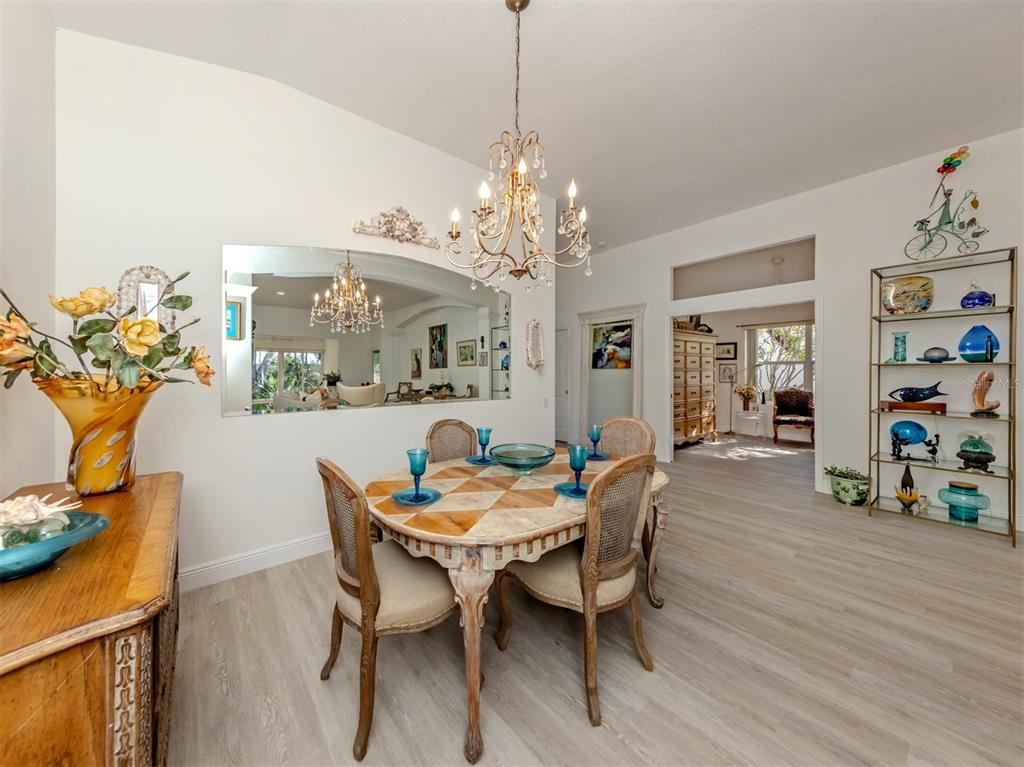 A dining room features a chandelier, a large wall mirror, and a decorative display shelf — 404 PINEWOOD LAKE DRIVE, VENICE, FL