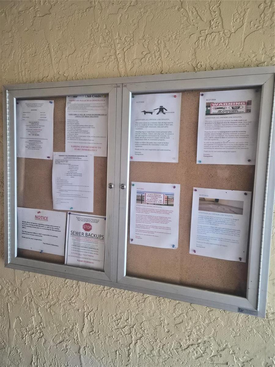 A wall-mounted, glass-enclosed cork bulletin board displays several notices and community rules — 3252 Foxcroft Road # 113, Miramar FL 33025, MIRAMAR, FL