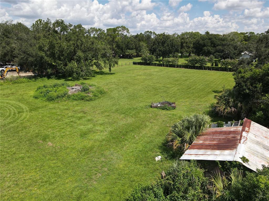 An aerial view shows a large, grassy lot with a small shed and scattered trees — 6043 S ORANGE BLOSSOM TRAIL, DAVENPORT, FL