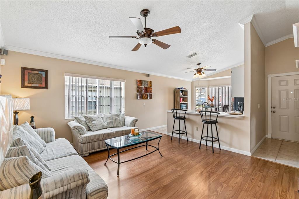A living room with wood-look flooring, a sofa, a coffee table, and a kitchen breakfast bar — 1967 GARWOOD DRIVE, ORLANDO, FL