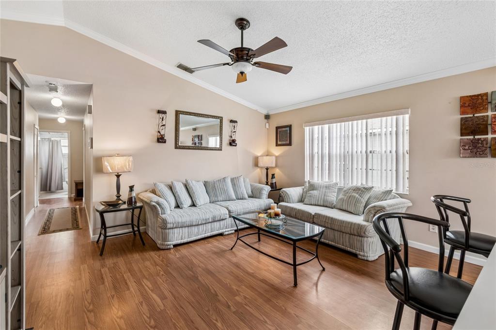 A living room features two striped sofas, a glass coffee table, and wood-look flooring — 1967 GARWOOD DRIVE, ORLANDO, FL