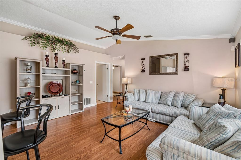 A living room features wood flooring, a ceiling fan, a striped sofa, and shelving units — 1967 GARWOOD DRIVE, ORLANDO, FL