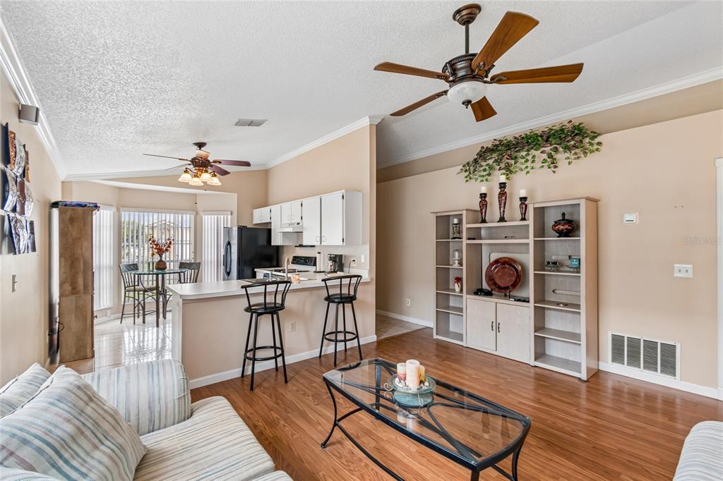 An open-concept living room and kitchen featuring wood-look flooring, a ceiling fan, and bar seating — 1967 GARWOOD DRIVE, ORLANDO, FL