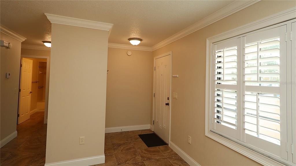 An entryway features tile flooring, a white front door, and a window with plantation shutters — 1915 SW 34TH COURT, OCALA, FL