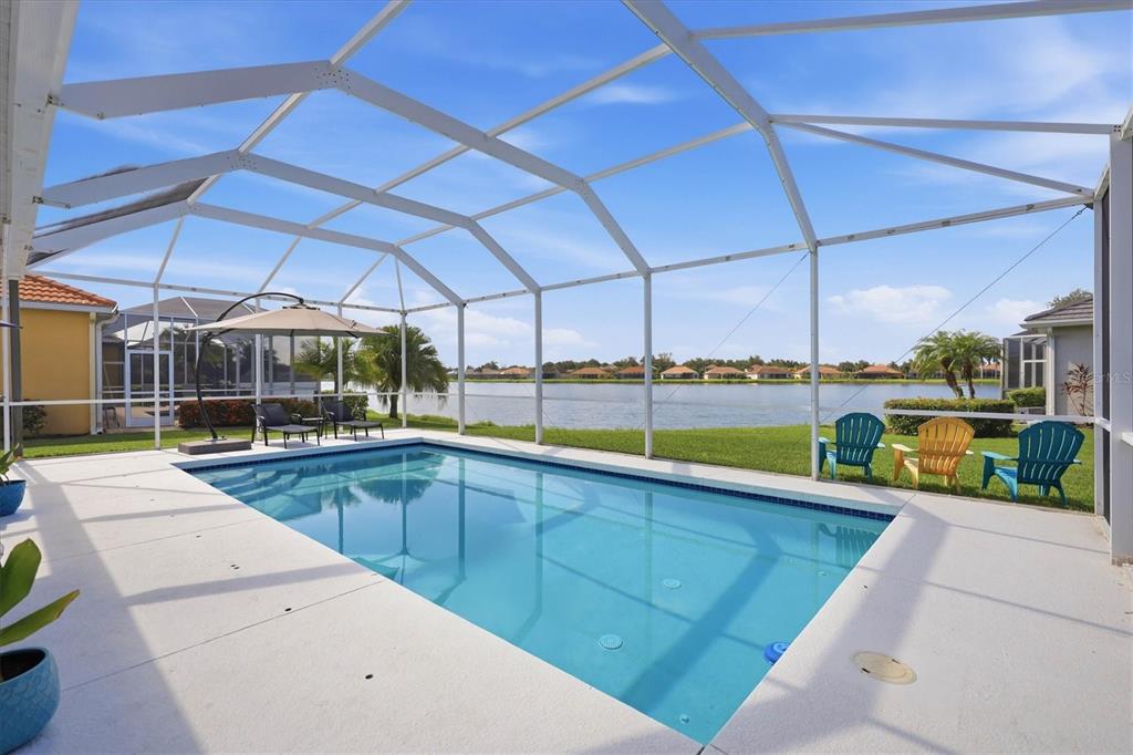 A screened-in swimming pool overlooks a lake behind a residential home — 6904 74TH STREET CIRCLE E, BRADENTON, FL